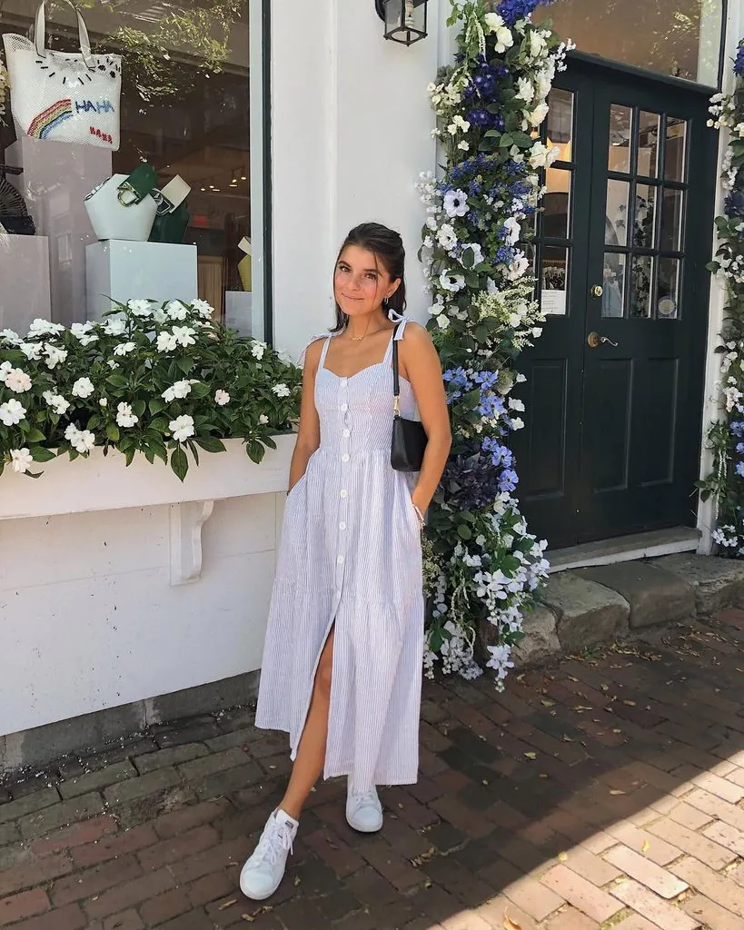 woman in blue striped midi dress standing outside shop with flowers