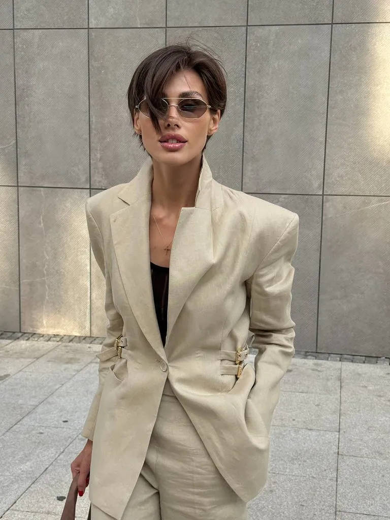 woman with short hair wearing a beige linen blazer suit and sunglasses
